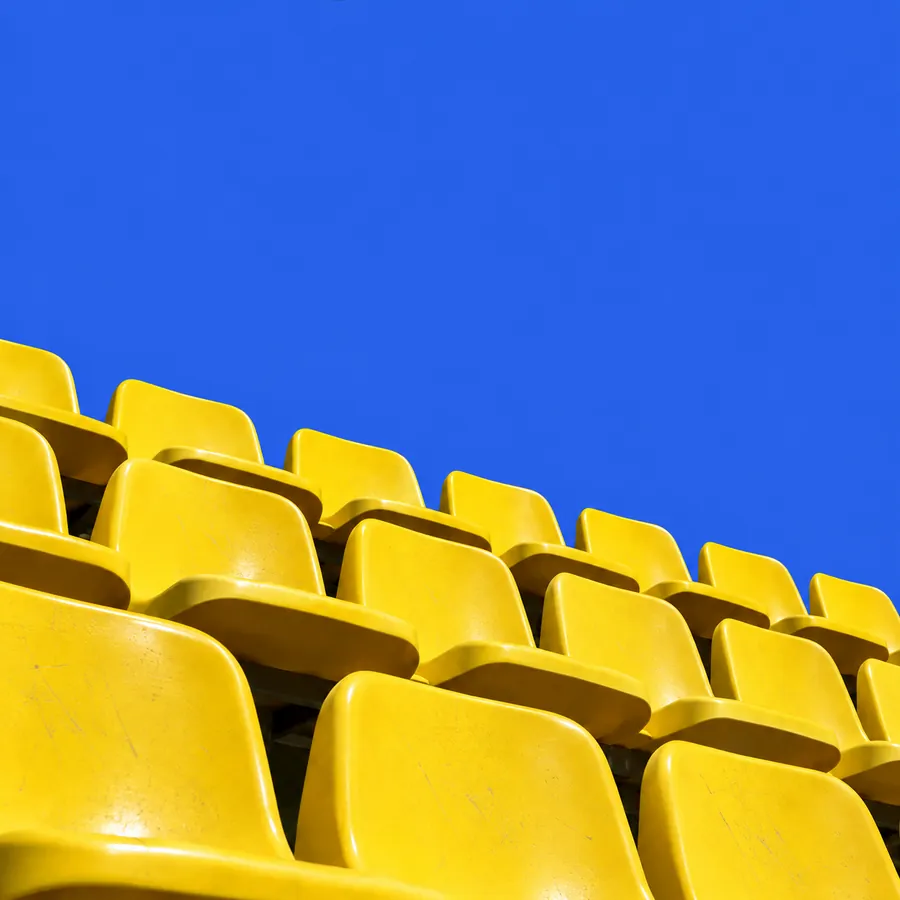 Fileiras de assentos amarelos de estádio contra um céu azul