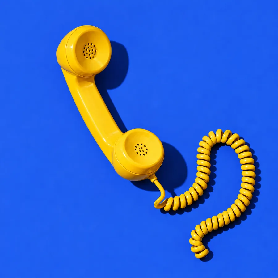 A yellow telephone handset on a cobalt blue backdrop