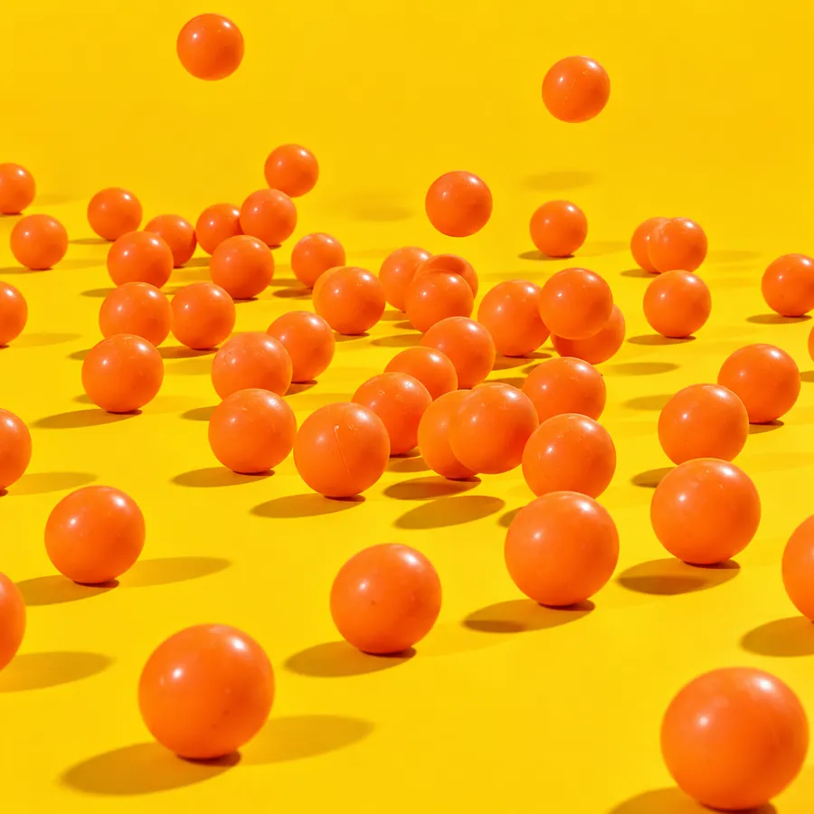 Orange ping pong balls bouncing across a yellow floor