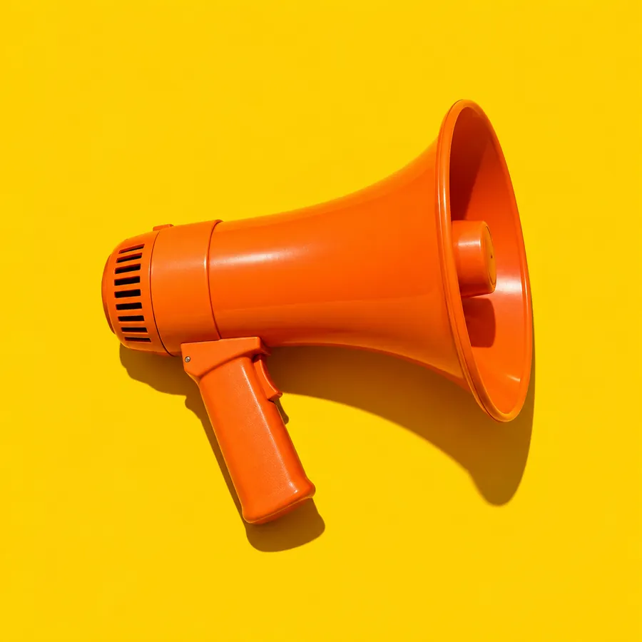 An orange megaphone lying on a yellow backdrop