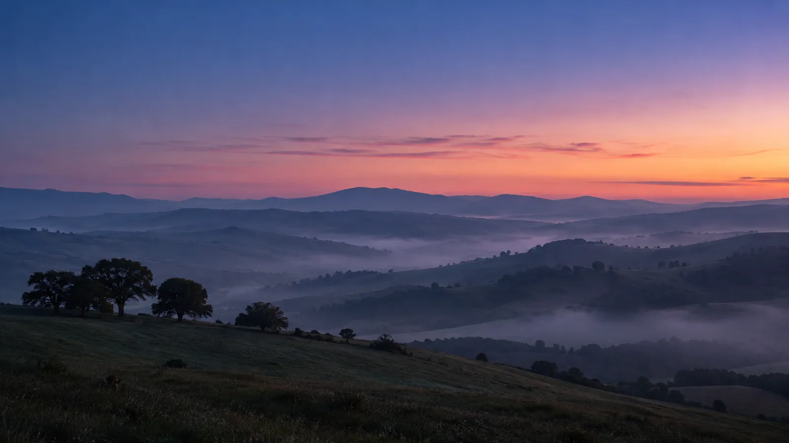 Layered hills at blue hour with mist in the valleys